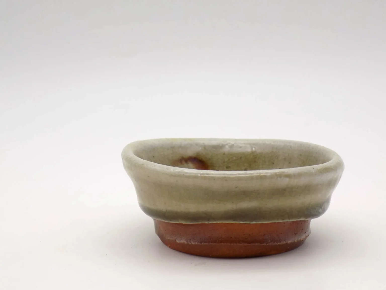Hand thrown ochoko cup with ash orange glaze side view by Timi Lantos Ceramics