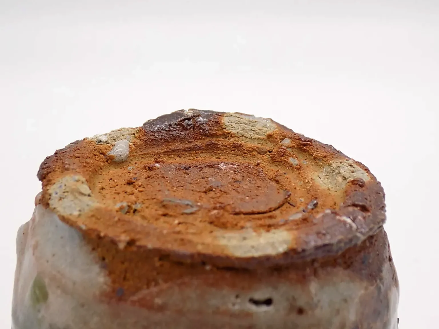 Bottom of a hand crafted shino sake cup orange rusty color