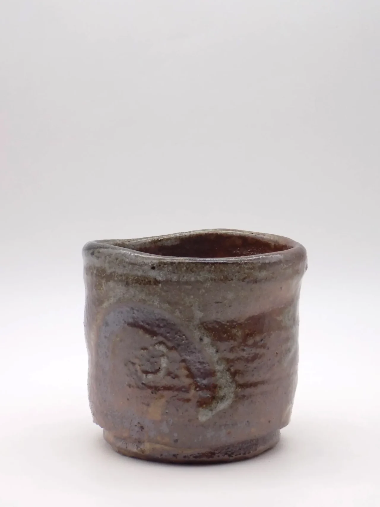an orange assymetric orange cup looks made of sandy clay