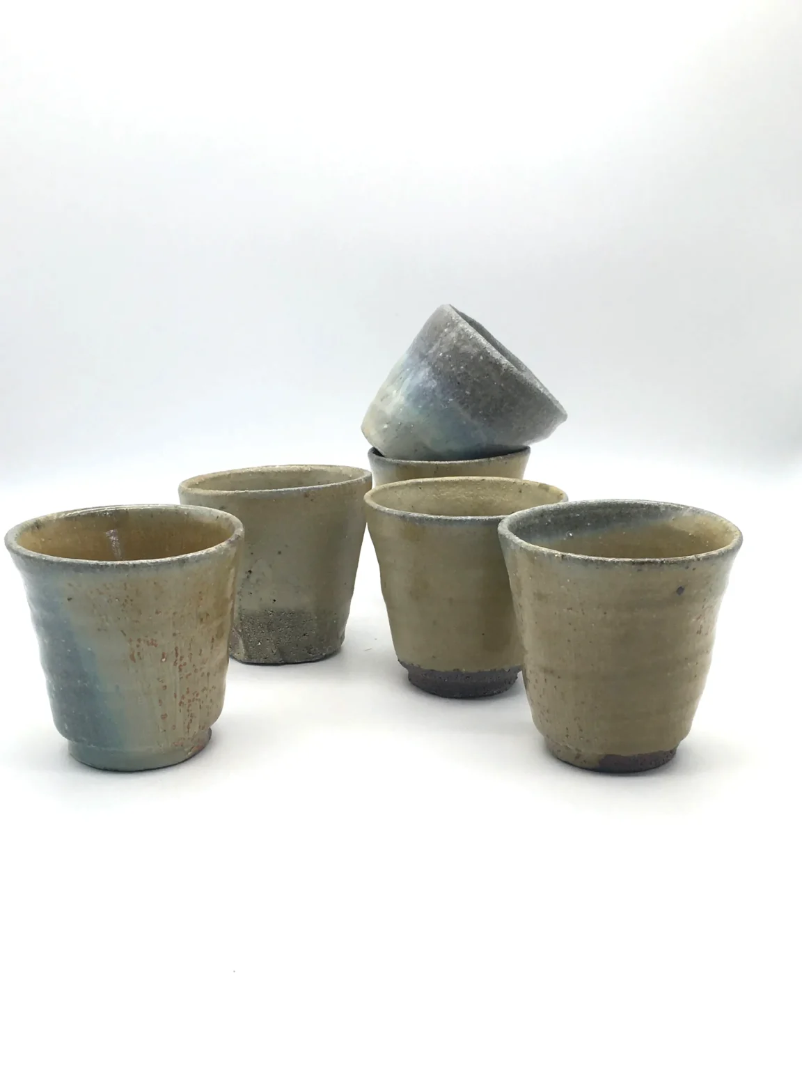 Group view of rustic tea cups with beige ash glaze and grey tones by Timi Lantos Ceramics