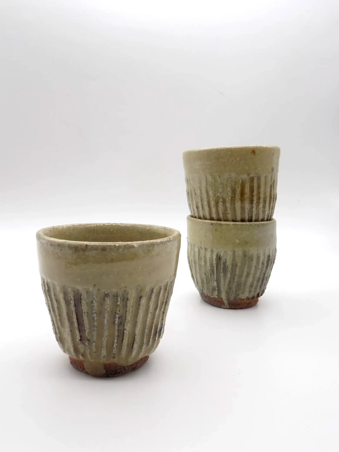 Hand thrown yunomi tea cup with ash glaze and hand carved beige surface by Timi Lantos Ceramics